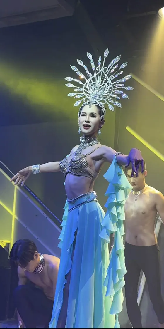 Cabaret performer in a silver starburst headdress and blue gown during the closing number